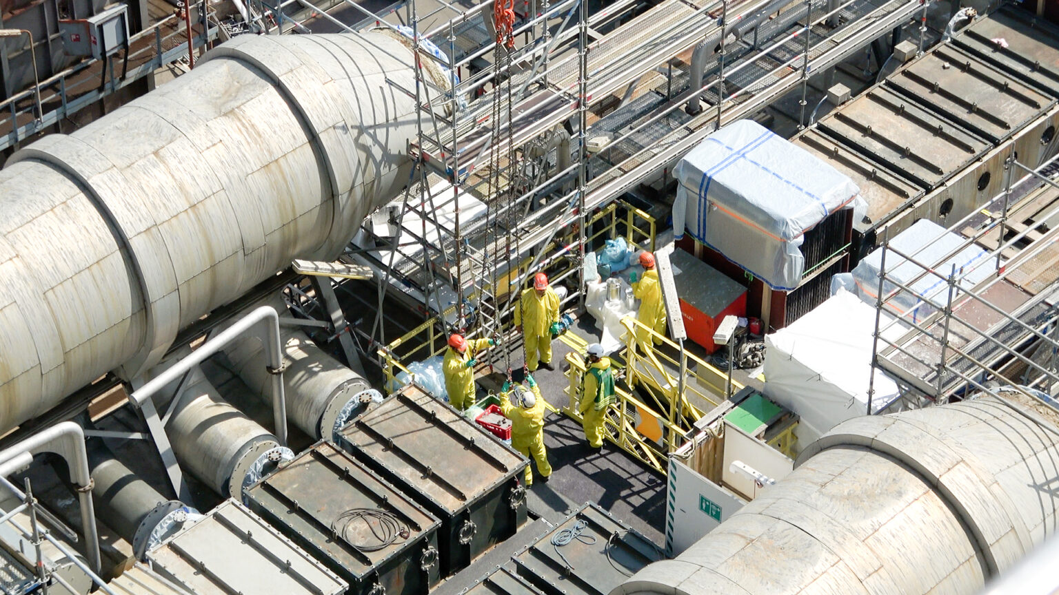 Monteure von Kremsmüller in Säureschutzanzügen am Dach der Rauchgasreinigungsanlage SNOx der OMV bei Umbauarbeiten